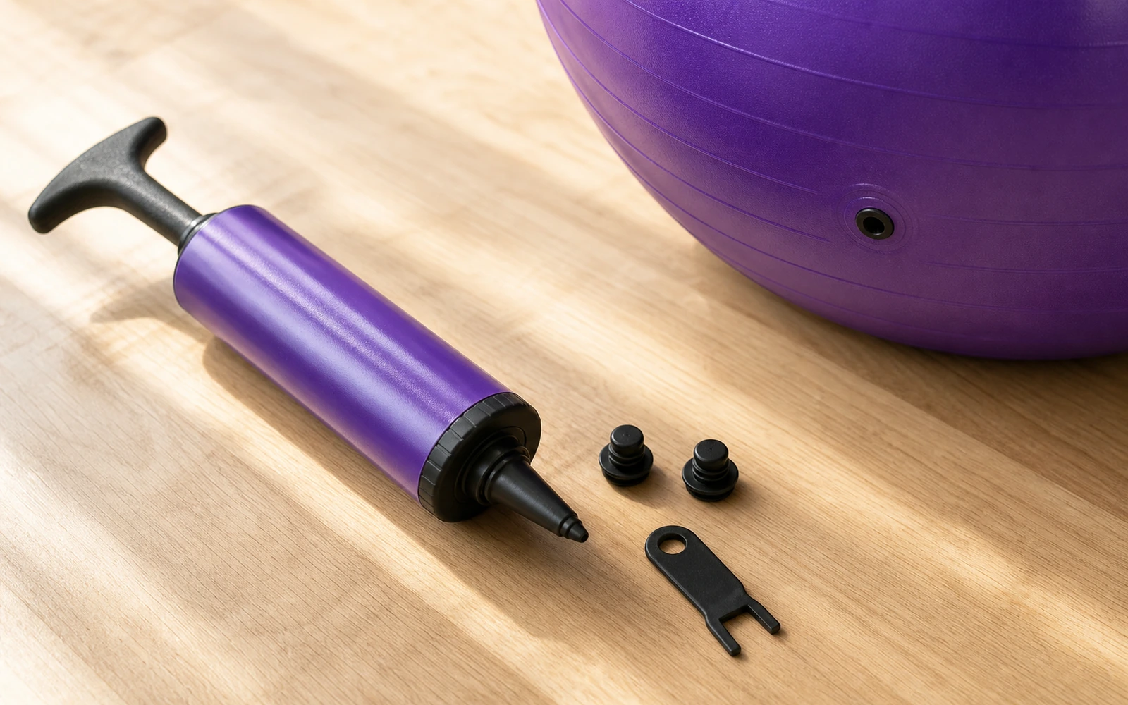 A hand pump and sealing plugs laid out beside a partly inflated ball